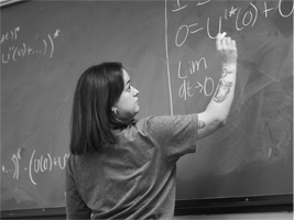 female student writing on chalkboard