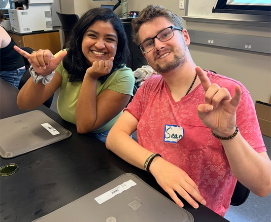 two students doing roadrunner hand sign
