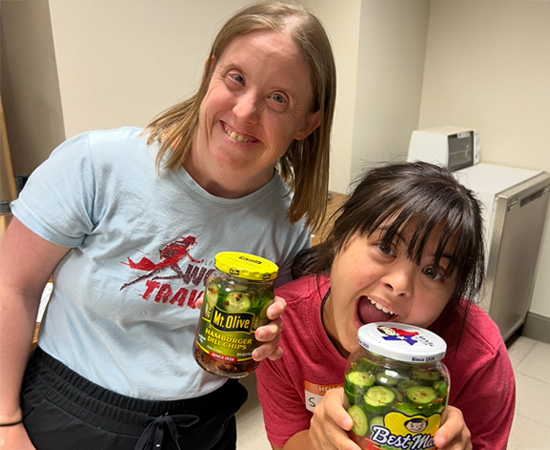 two people holding pickle jars