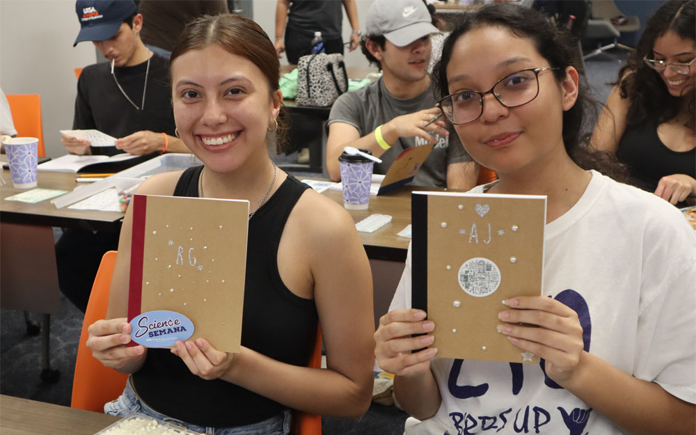 students holding up notebooks