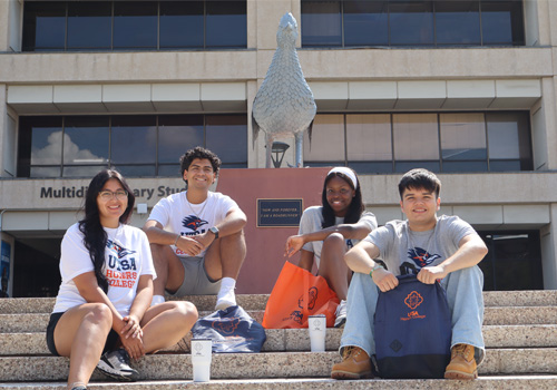 four students on steps by Rowdy statue