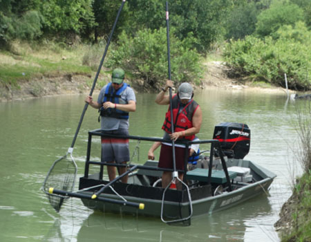 people with nets in boat on creek