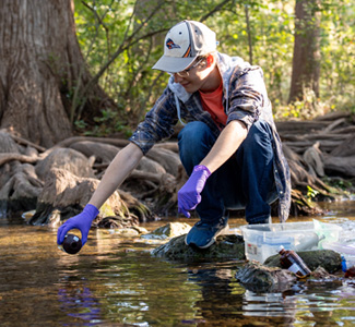 Ronny Saunders scooping water sample from creek