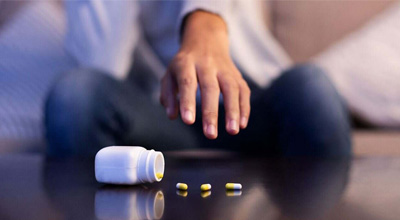 hand hovering over spilled bottle of drugs