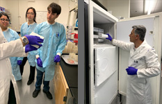three students in lab and person at lab hood