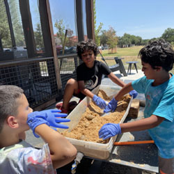 campers working with sand to create rivers