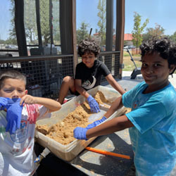 campers working with sand to create rivers