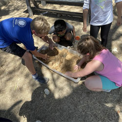 campers working with sand to create rivers