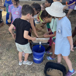 campers working with sand to create rivers