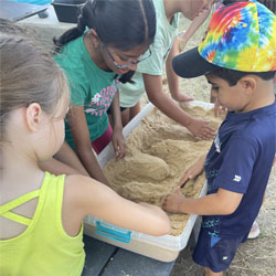 campers working with sand to create rivers