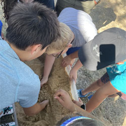 campers working with sand to create rivers