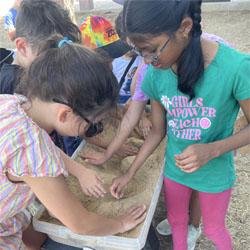 campers working with sand to create rivers