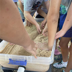 campers working with sand to create rivers