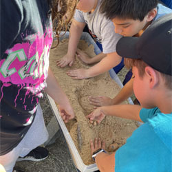 campers working with sand to create rivers