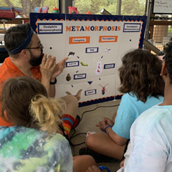 campers on floor around a metamorphosis whiteboard