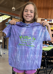 camper holding up tie dye shirt