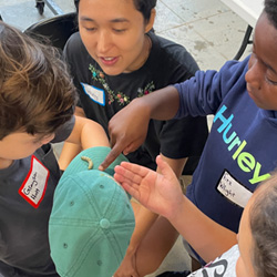 campers looking at caterpillar on a hat brim