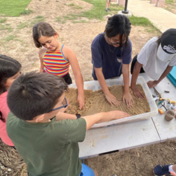 campers working with sand to create rivers