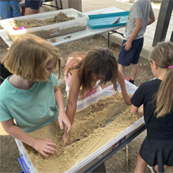 campers working with sand to create rivers