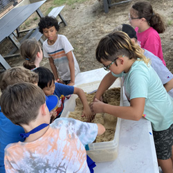 campers working with sand to create rivers