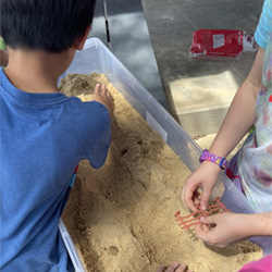 campers working with sand to create rivers