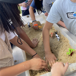 campers working with sand to create rivers