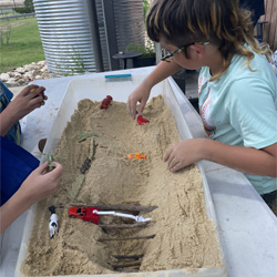 campers working with sand to create rivers