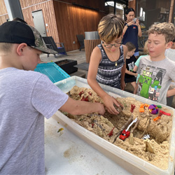 campers working with sand to create rivers