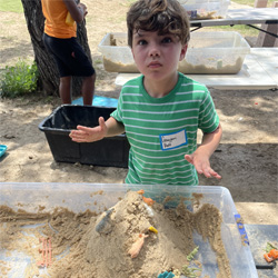 camper working with sand to create rivers