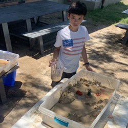 campers working with sand to create rivers