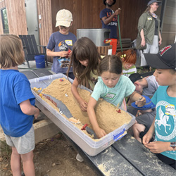 campers working with sand to create rivers