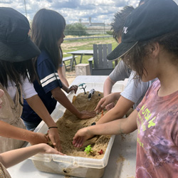 campers working with sand to create rivers