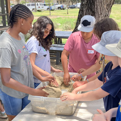 campers working with sand to create rivers