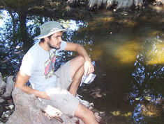 student sitting by creek