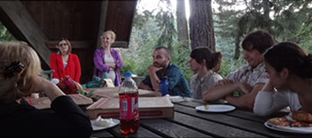 participants eating pizza at picnic table