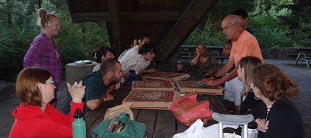 participants eating pizza at picnic table