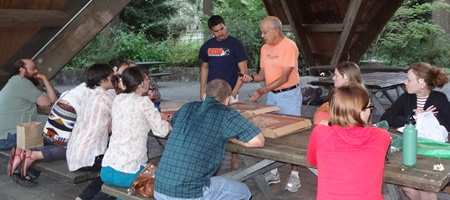 participants eating pizza at picnic table